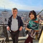 Wide panoramic view of Florence's terracotta rooftops from the open balcony of Brunelleschi's Dome, with Giotto's Bell Tower visible in the foreground.