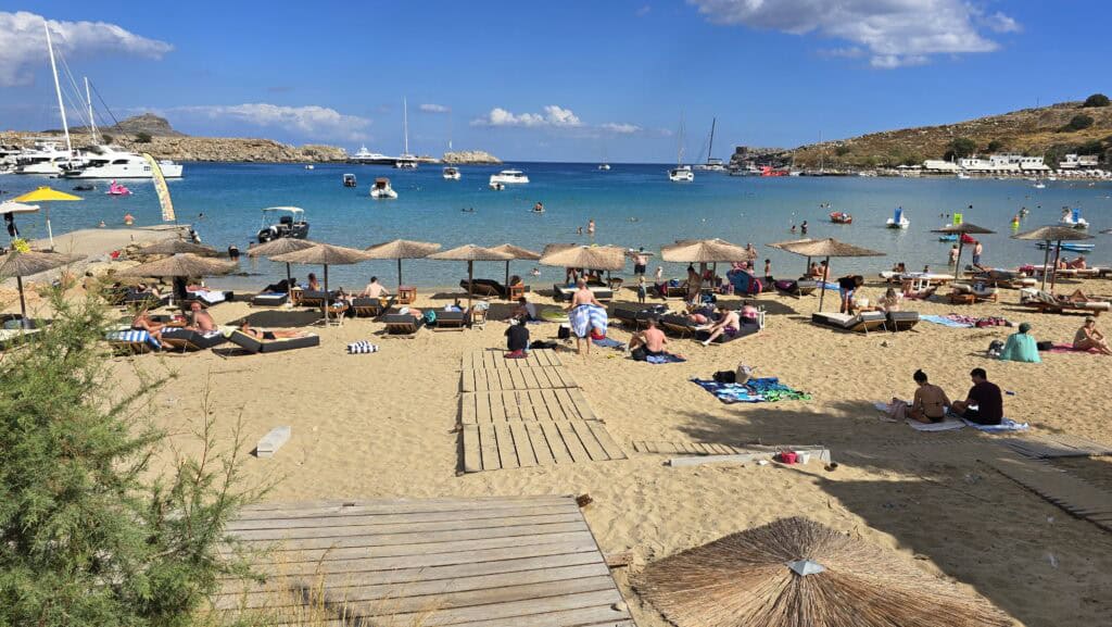 Illustrating the common layout of Lindos Main Beach: the paid sunbeds and umbrellas typically occupy the prime beachfront space, while the free, unorganized area is often situated just behind the rental rows.