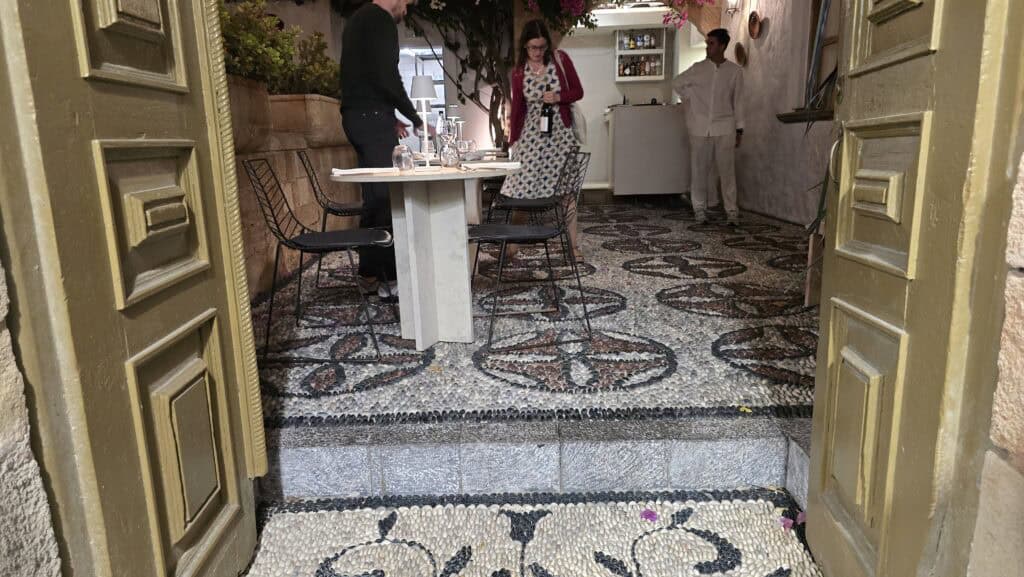 Lindos, Rhodes: The Complete Guide to What to See, Acropolis, and the White Village's Beaches 7 👣 The Ancient Art Underfoot: Exploring Traditional Lindian Architecture
Another fascinating aspect of walking through Lindos is the discovery of the ancient architecture right under your feet. When the doors of restaurants or various buildings are open, it’s worth pausing to admire the beautiful pebble mosaic floors (known locally as chochlaki). These intricate patterns, often featuring designs or symbols made from smooth black and white stones, instantly showcase Lindos's rich and ancient history. Having the opportunity to sneak a peek inside courtyards or local establishments provides a glimpse into this traditional art form. It's a truly beautiful and rewarding part of the exploration—a subtle sign of the historical depth beneath the modern, white facade.