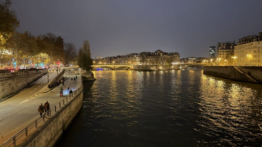 View of the Seine River promenade in Paris at dusk, showing the walkable area and early evening lights during the autumn season.