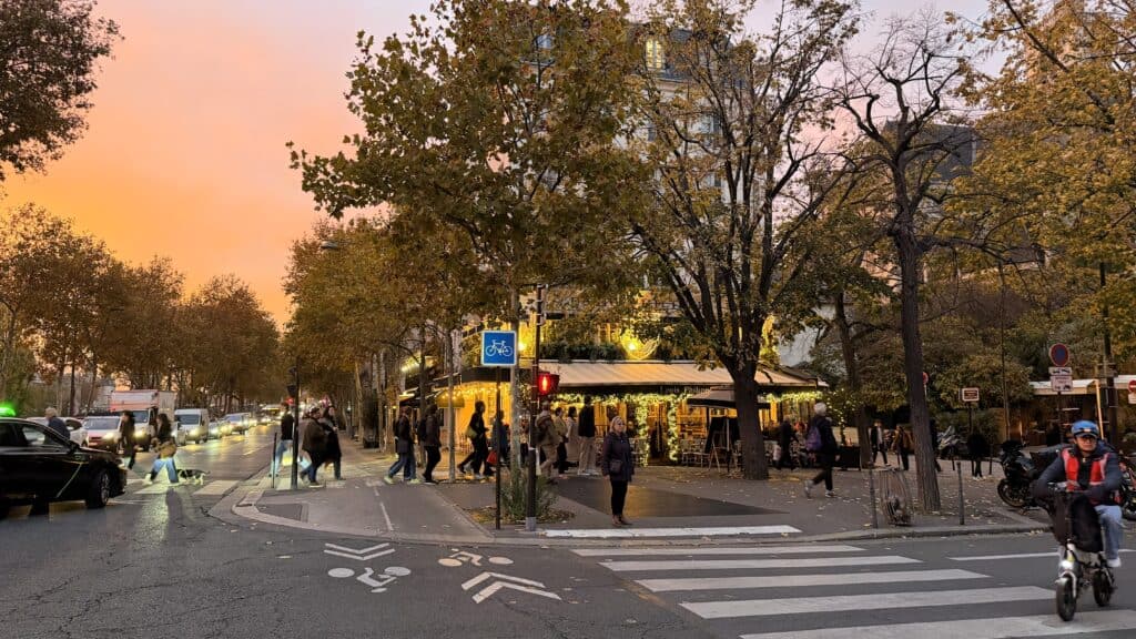 Parisian street at sunset during Gabriel's evening walk, showing the warm autumn light and classic buildings.