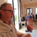 Gabriel, the travel companion, tasting a local Rhodian red wine in a Lindos restaurant, confirming the sensory journey and group's E-E-A-T.
