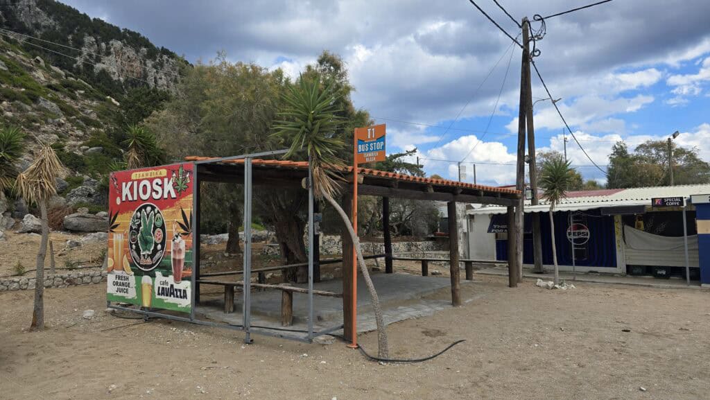 Road view near Tsampika Beach showing the accessibility and proximity of the bus stop for public transport users.
