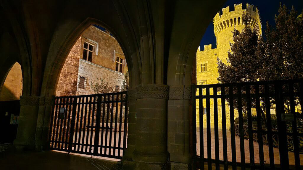 Night view of the closed gates and illuminated courtyard of the Palace of the Grand Master in Rhodes Old Town.