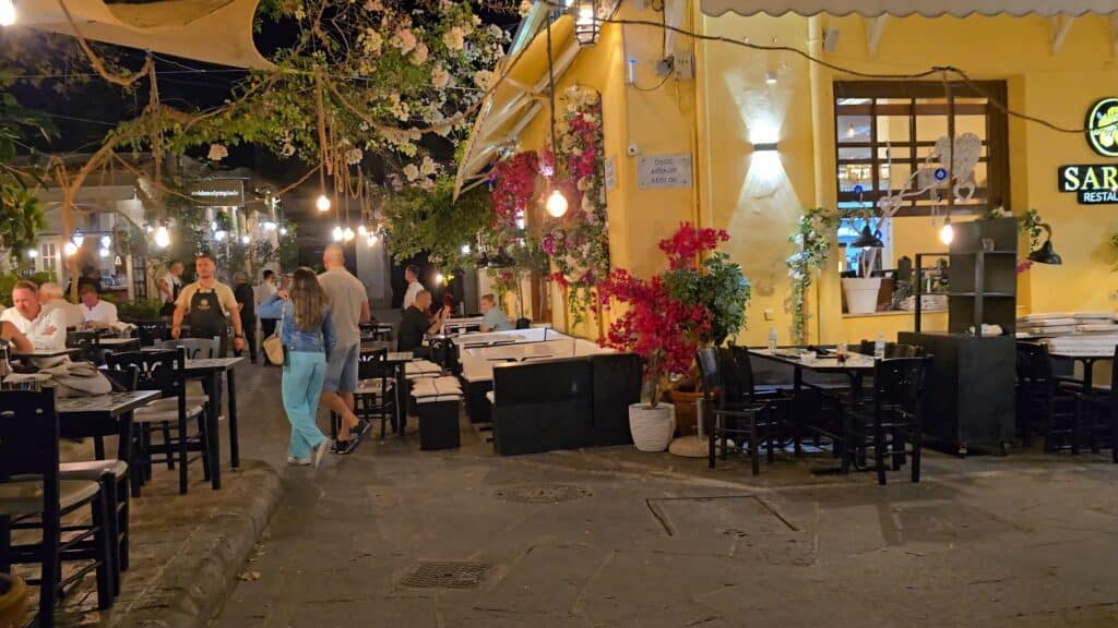 Exterior view of Sarris Restaurant in Rhodes Old Town, featuring outdoor tables along the street and decorative climbing flowers.