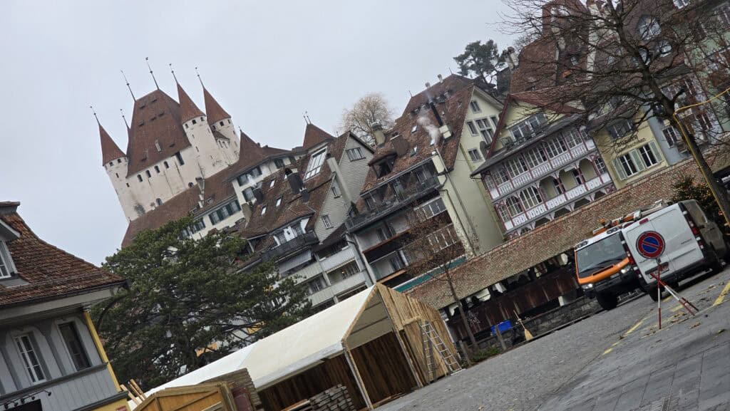 A view of the historic Thun Castle and traditional Swiss buildings in Thun, Switzerland, under a grey winter sky, captured during a trip by Ila from Tripilare.