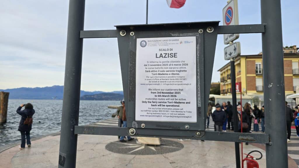 An official service suspension notice posted at the Lazise Ferry Dock. The sign, dated 2025-2026, indicates that main passenger ferry lines will be inactive, confirming the general Lake Garda winter transport limitation. This serves as a vital reminder to plan alternative travel (car/bus) during the low season.