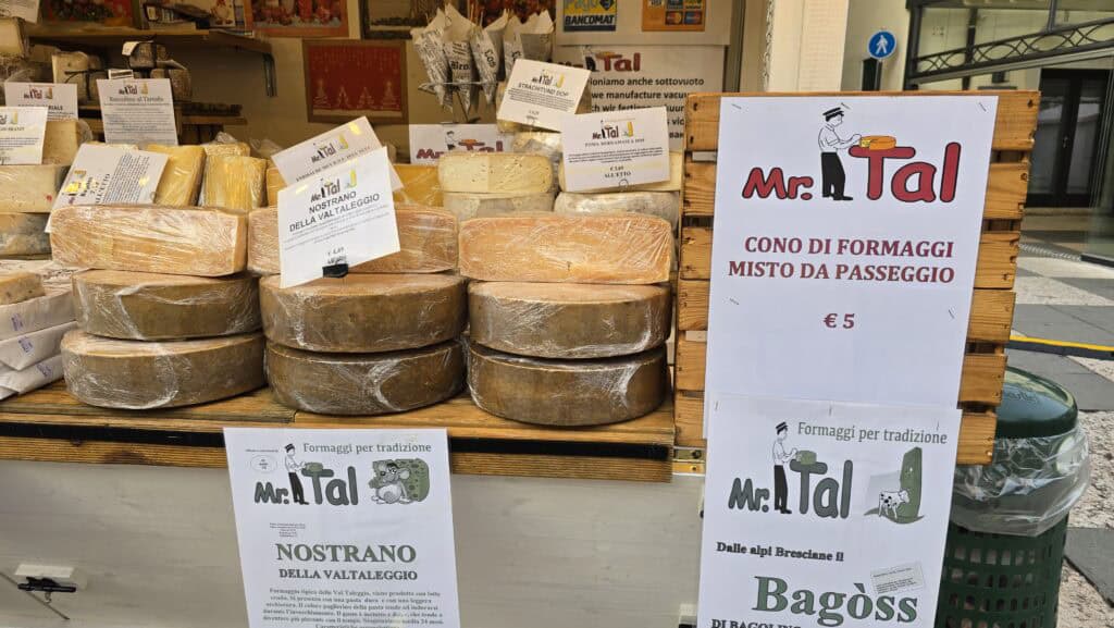 A clear photograph of a mixed cheese cone (formaggio misto) takeaway snack from a Lazise Christmas Market food stall. The cone is filled with various cubed cheeses, perfect for enjoying while walking.