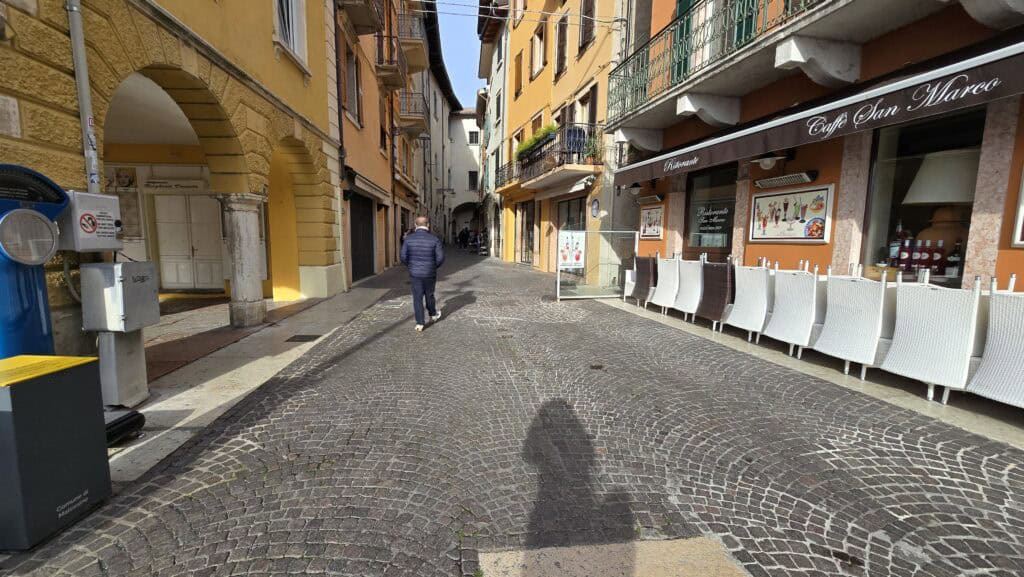Gabriel walking through the empty historic center of Malcesine in winter. The photo highlights the quiet atmosphere and a closed bar, confirming the low-season tranquility of the town.