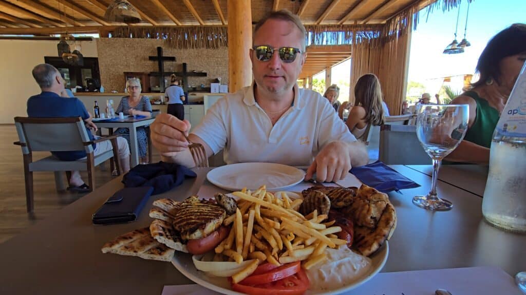 A large mixed meat platter for two shared by Ila and Gabriel at Culinarium Beach Restaurant in Vlycha Beach, Lindos, featuring grilled meats, fries, and pita bread. 