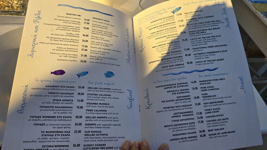 The dinner menu at Fisherman's House in Ano Mera, Mykonos, showing prices for fresh fish, seafood, and pasta during July 2025.