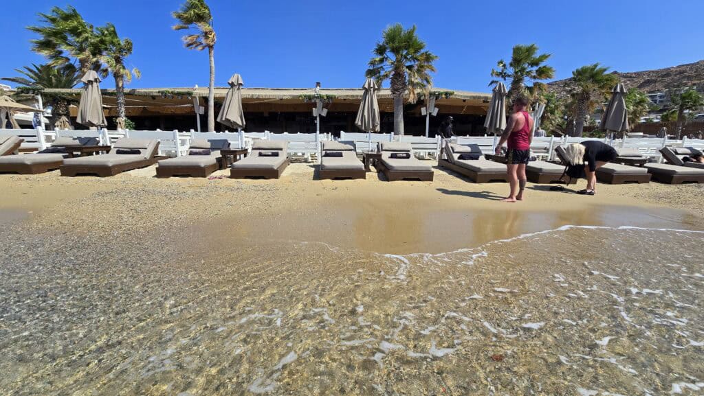 Your Guide to Paradise Mykonos: Is It a Party Beach or a Relaxing Escape? 8 View from inside the water looking towards the shoreline and the Tropicana Club at Paradise Beach, Mykonos.