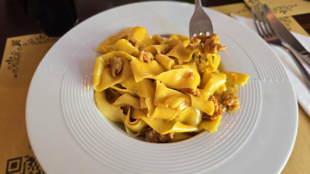 Monza: The Royal Escape Just a Stone's Throw from Milan 1 A full plate of Pappardelle alla Monzese with a rich yellow saffron sauce and pieces of Italian luganiga sausage.