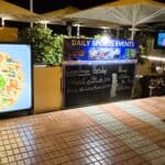 Chalkboard schedule displayed outside a bar in Tenerife showing live sports and music timings.