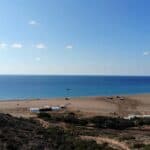 Panoramic view of Prasonisi beach illustrating the vast size of the free public beach area compared to the small, organized section of only three rows of sunbeds.