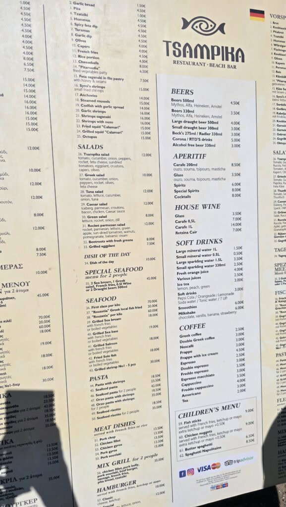 Menu board for Tsampika Restaurant - Beach Bar on Rhodes, clearly showing prices for seafood, meat dishes, salads, and drinks. The Special Seafood for 2 people is highlighted at €45.00. (October 2025)