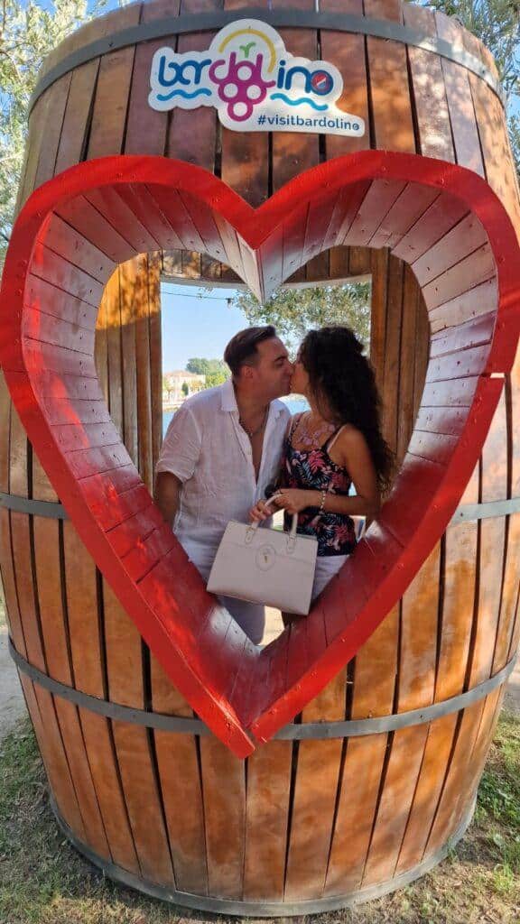 Top 7 beautiful Things to do in Bardolino Lake Garda Italy: not only wine 2 A romantic couple kissing inside the giant heart-shaped wine barrel in Bardolino, Lake Garda, captured by Ila from Tripilare.