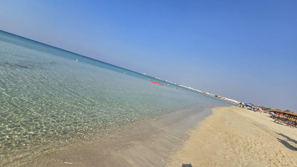Experiencing Torre Lapillo, Salento, Puglia: Honest Travel Guide (Beach, Costs, & Real Experience) 2 Early morning beach walk along the long coastline of Torre Lapillo, Puglia, Italy, with calm turquoise waves.